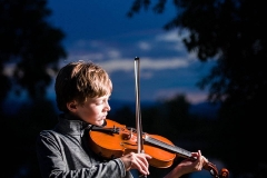 young boy playing violin outdoors