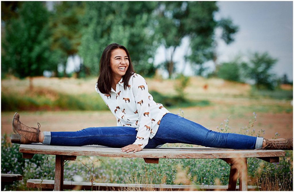 senior girl doing the splits in blue jeans
