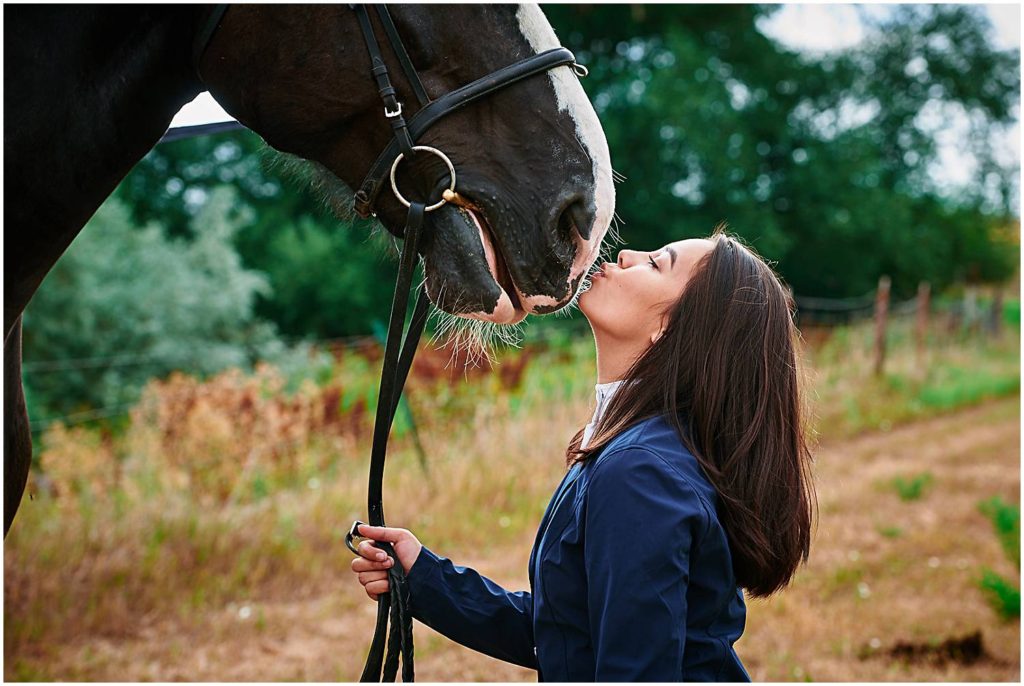Senior girl smooching a giant horse nose