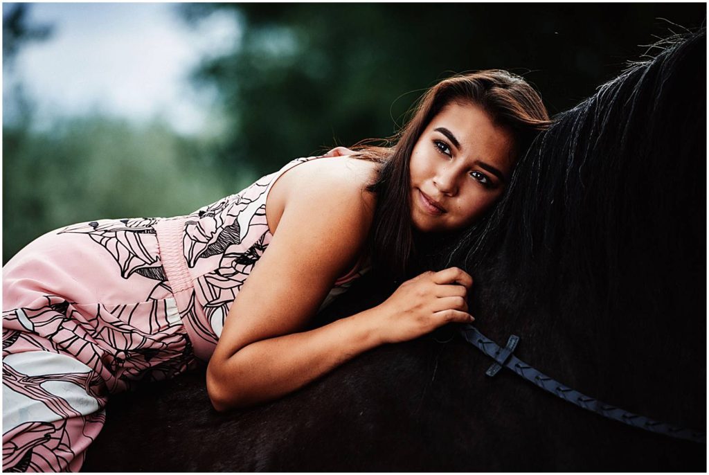 senior girl lying on horse